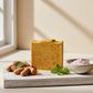 Handcrafted turmeric soap bar with turmeric root, pink clay and spearmint leaves on a wooden surface